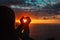 Tourist enjoy sunset at sea, making heart with hands