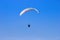 Tourist flying on a paraglider flying in the blue sky on a bight day. The sportsman paragliding