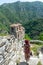 Tourist freelancer woman with glamour hat standing on medieval fortress. Lady hipster journalist with backpack on eastern