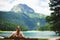 Tourist girl enjoys the magical view sitting on a wooden bench on the shore of a turquoise lake in the mountains.