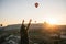 A tourist girl in a hat admires hot air balloons flying in the sky over Cappadocia in Turkey. Impressive sight.