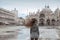 Tourist girl with long blowing hair in Piazza San Marco in front