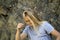 A tourist girl with long white hair climbs the rocks