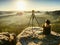 Tourist girl photographer look at misty mountains from rock