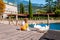 Tourist girl sitting on a wooden pier with two white swans walking around on promenade of Garda lake in Riva del Garda, Lombardy,