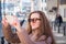 Tourist girl in sun-protection glasses photographing the sights of city streets