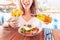 Tourist girl tries Greek cuisine at a local restaurant. On the table traditional salad Horiatiki and Gyros in Pita