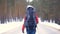 The tourist girl is turning around and starts her way along the road in the winter forest.