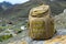 Tourist green backpack standing on a stone on a mountainside