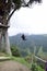 Tourist having fun swinging on Giant Swing. View of green mountains and trees in background. Banos