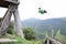 Tourist having fun swinging on Giant Swing. View of green mountains and trees in background. Banos