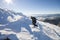 Tourist hiker climber in winter clothing with backpack climbing dangerous rocky steep mountain slope covered with deep snow, white