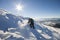 Tourist hiker climber in winter clothing with backpack climbing dangerous rocky steep mountain slope covered with deep snow, white