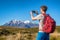 Tourist hiker man taking picture with phone of mountains in New Zealand during hike on Tongariro Alpine crossing track
