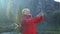 Tourist hiker senior woman backpacker on rock enjoying taking selfie with smartphone near the view of mountain lake