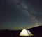 Tourist hikers tent in mountains at night with milky way stars i