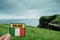 Tourist holding badge with sign Ireland and Irish flag in focus, Cliff of Moher out of focus.