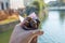 Tourist holding a portion of chestnuts in a cone with river view.