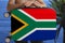 Tourist holds with two hands a suitcase with the national flag of South Africa, a symbol of vacation, immigration, political