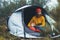 Tourist hugging red shiba inu in camp tent on background froggy rain forest, hiker woman with puppy dog in mist nature trip