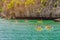 Tourist kayaking in blue Idyllic turquoise ocean to explore near the island with lush green jungle trees and lime stone mountains