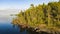 Tourist kayaks stand by the picturesque rocky coast with a pine forest. Stunning island in a large lake.