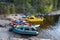 Tourist kayaks and a yellow boat in a rocky and wooded bay of the lake