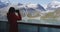 Tourist looking at Alaska Glacier Bay nature using binoculars on cruise ship