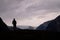 Tourist looking at the rocky mountains standing under the gloomy sky