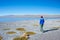 Tourist looking at the stunning landscape of salty frozen lake on the Andes, road trip to the famous Uyuni Salt Flat, travel desti