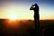 Tourist make frame with palms and fingers on both hands. Hiker on rocky cliff, daybreak in rocky mountains.