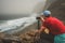 Tourist making photograph of cliff coastline with ocean waves from Cruzinha to Ponta do Sol. Huge mountains on the