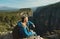 Tourist man sitting on cliff and overlooking big canyon, panoramic view