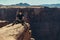 Tourist man sitting on the mountain cliff edge rock and enjoy the view after hiking at hot summer day at Grand Canyon