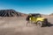 Tourist man standing on yellow four wheel car in desert