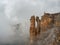 Tourist man stands on the cliff edge of Bermamyt plateau on high altitude under cloudy sky in foggy day. Rocks of Big Bermamyt