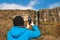 Tourist man taking pictures of Devil`s chimney waterfall, county Sligo, Ireland. Warm sunny day, Cloudy sky. Travel and outdoor