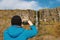 Tourist man taking pictures of Devil`s chimney waterfall, county Sligo, Ireland. Warm sunny day, Cloudy sky. Travel and outdoor