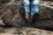 Tourist in old worn out hiking boots and blue jeans in a rough mountain terrain. Long journey concept. Legs in old shoes on hard