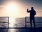 Tourist photograph on sea mole. Hiker take photos of morning sea. Tourist on wooden board