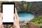tourist photographs Kerid lake in volcanic crater
