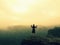 Tourist with poles in hands is standing on rock and watching into orange misty landscape. National rock empire park, melancholic