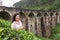 A tourist poses in a tea plantation near the famous nine-arch bridge in Sri Lanka. Tourism in picturesque places