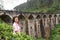 A tourist poses in a tea plantation near the famous nine-arch bridge in Sri Lanka. Tourism in picturesque places