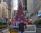Tourist posing before a Christmas display with tree, gifts and Nutcrackers in Fox Square on 6th Avenue in New York City