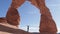 Tourist Raises His Hands Up In A Delicate Arch Of Orange Rock In National Park