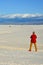 A tourist in red clothes on a background of sand dunes photographs
