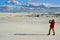 A tourist in red clothes on a background of sand dunes photographs