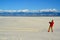 A tourist in red clothes on a background of sand dunes photographs