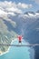 Tourist with red hoody sit on swing bridge looking at glacier reservoir in Austria zillertal Alps